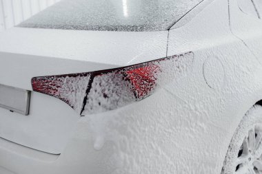 Köpüklü modern yıkama ve beyaz bir arabanın yüksek basınçlı suyu. Araba yıkama