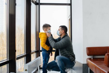 Karantina sırasında çocuklu bir baba maske takıyor. Salgın, koronavirüs.