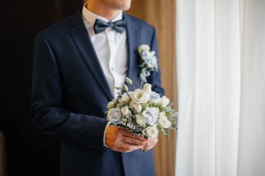 Güzel ve sofistike bir düğün buketi gelini damadın yanında tutuyor. Düğün buketi ve yüzükler.