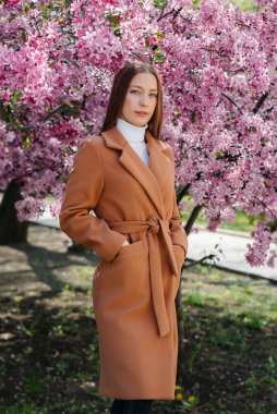 Güzel bir genç kız, bahar günü çiçek açan bir elma bahçesinde yürür. Yaşam tarzı, eğlence.