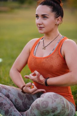 Gün batımında parkta yoga yapan genç bir kız. Sağlıklı yaşam tarzı