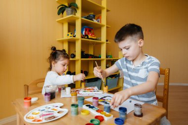 Bir erkek ve bir kız birlikte oynayıp resim yapıyorlar. Eğlence ve eğlence. Evde kal.