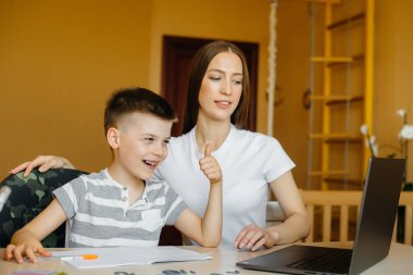 Bir anne ve çocuğu evde bilgisayarın önünde uzaktan öğrenme ile meşguller. Evde kal, çalış.