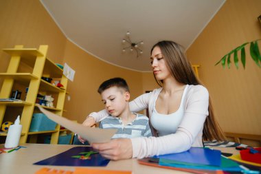 Genç bir anne evde oğluyla ev ödevi yapıyor. Ebeveynler ve eğitim