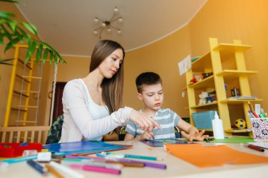 Genç bir anne evde oğluyla ev ödevi yapıyor. Ebeveynler ve eğitim