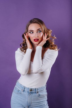 Genç ve güzel bir kız, mor bir arka planda stüdyoda duygularını ve gülümsemelerini gösterir. Reklam için kızlar