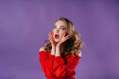 Genç ve güzel bir kız, mor bir arka planda stüdyoda duygularını ve gülümsemelerini gösterir. Reklam için kızlar