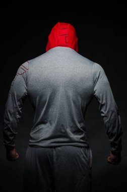 Stüdyoda kapüşonlu karanlık bir arka plana karşı duran sportif bir adam. Spor, güzellik