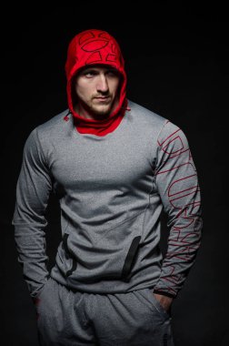 Stüdyoda kapüşonlu karanlık bir arka plana karşı duran sportif bir adam. Spor, güzellik