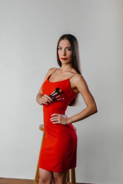 Güzel genç bir makyöz, Stüdyoda beyaz bir arka planda püskülleriyle poz veriyor. Makyaj