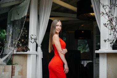 Güzel bir genç kız güzel bir evin verandasında duruyor..