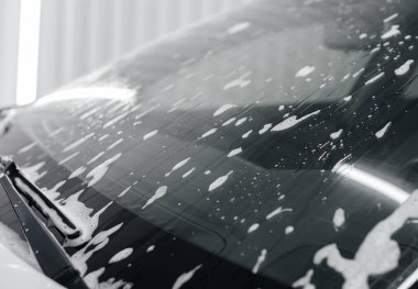 Köpüklü modern yıkama ve beyaz bir arabanın yüksek basınçlı suyu. Araba yıkama