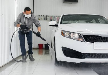 Köpüklü modern yıkama ve beyaz bir arabanın yüksek basınçlı suyu. Araba yıkama