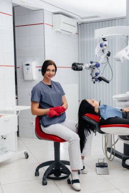 Dişçi mikroskoptan bakar ve hastayı ameliyat eder.