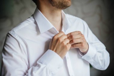 Şık genç adam kol düğmelerinin düğmelerini ilikliyor. Biçim