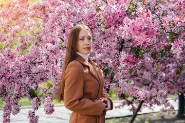 Güzel bir genç kız, bahar günü çiçek açan bir elma bahçesinde yürür. Yaşam tarzı, eğlence.