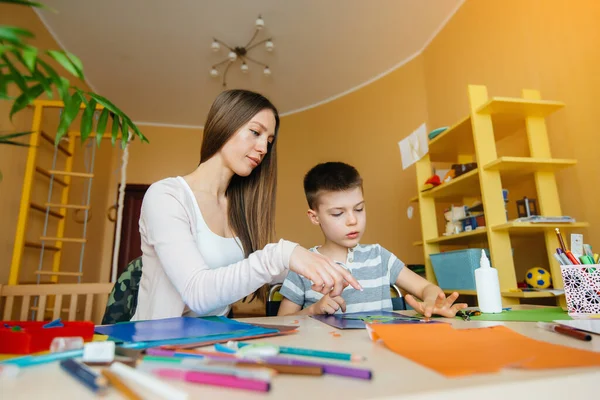 Genç bir anne evde oğluyla ev ödevi yapıyor. Ebeveynler ve eğitim