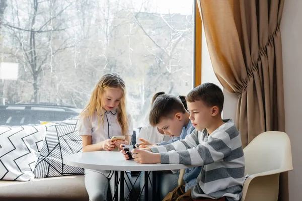 Crianças Sentam Uma Mesa Café Jogam Telefones Celulares Conjunto Entretenimento — Fotografia de Stock