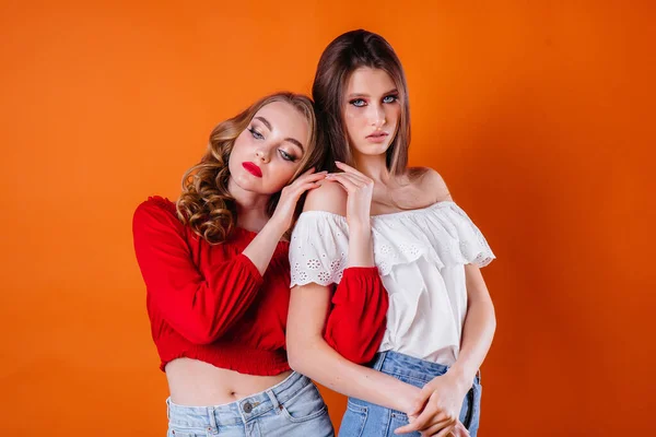 Две Молодые Красивые Девушки Показывают Эмоции Улыбки Студии Оранжевом Фоне — стоковое фото