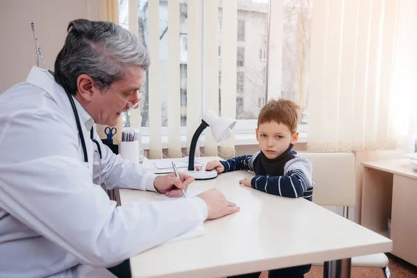 若い男の子が現代の診療所で経験豊富な医師の話を聞いて治療される ウイルスと伝染病 — ストック写真