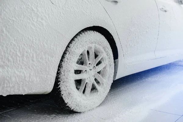 Modern washing of car wheels with foam and high water pressure. Car wash