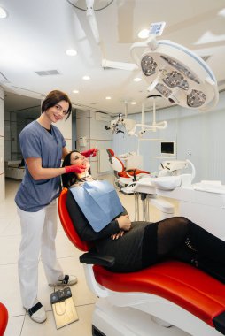 Genç bir doktor hastasının dişlerini tedavi eder. Dişçilik