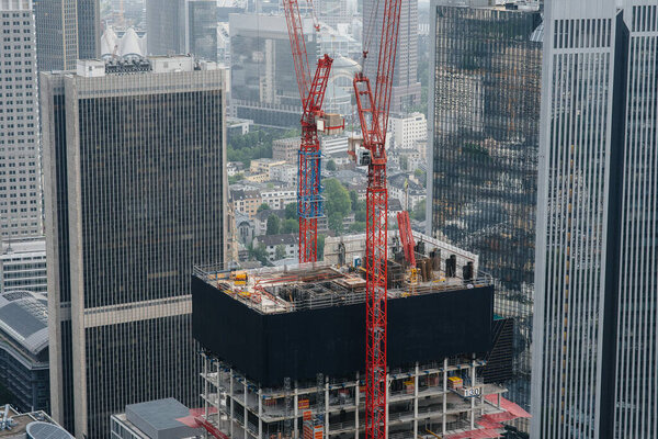 Construction of a modern high-rise skyscraper with cranes in the center of the metropolis. Construction