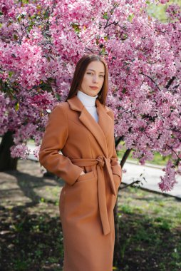 Güzel bir genç kız, bahar günü çiçek açan bir elma bahçesinde yürür. Yaşam tarzı, eğlence.