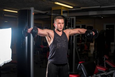 Genç bir sporcu spor salonunda fitness yapıyor. Fitness, vücut geliştirme