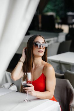 Güzel bir genç kız güzel bir evin verandasında oturur ve şarap içer. Tatil.