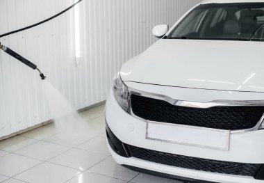 Köpüklü modern yıkama ve beyaz bir arabanın yüksek basınçlı suyu. Araba yıkama