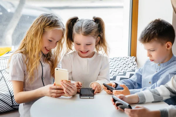 Los Niños Sientan Una Mesa Café Juegan Juntos Los Teléfonos —  Fotos de Stock