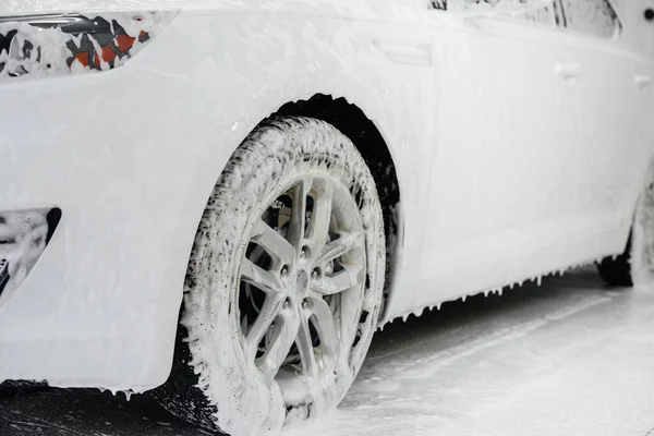 Modern washing of car wheels with foam and high water pressure. Car wash