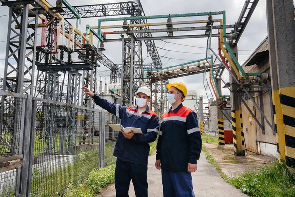 Engineers electrical substations conduct a survey of modern high-voltage equipment in the mask at the time of pandemia. Energy. Industry