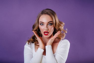 Genç ve güzel bir kız, mor bir arka planda stüdyoda duygularını ve gülümsemelerini gösterir. Reklam için kızlar
