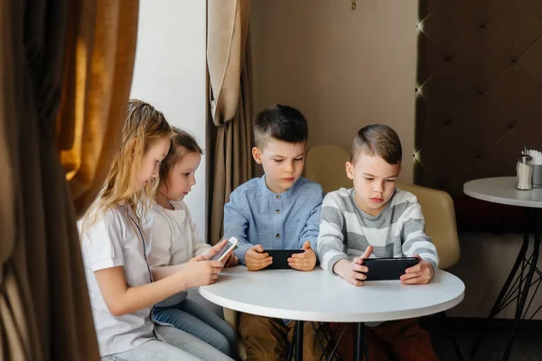 Çocuklar Bir Kafede Bir Masada Oturup Birlikte Cep Telefonu Oynarlar — Stok fotoğraf