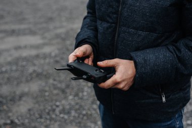 Genç bir adam helikopteri kontrol etmek için uzaktan kumanda tutuyor..