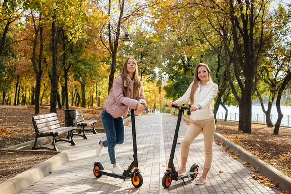 Két Fiatal Gyönyörű Lány Elektromos Robogózik Parkban Egy Meleg Őszi — Stock Fotó