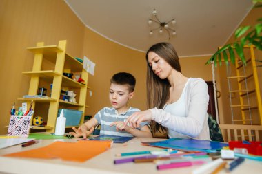 Genç bir anne evde oğluyla ev ödevi yapıyor. Ebeveynler ve eğitim