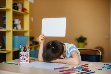 Okul çağındaki bir çocuk evde ödev yapar. Okulda eğitim.