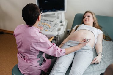Hamile bir kız klinikte karnının ultrasonuna giriyor. Tıbbi muayene