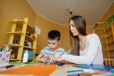 Genç bir anne evde oğluyla ev ödevi yapıyor. Ebeveynler ve eğitim