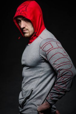 Stüdyoda kapüşonlu karanlık bir arka plana karşı duran sportif bir adam. Spor, güzellik