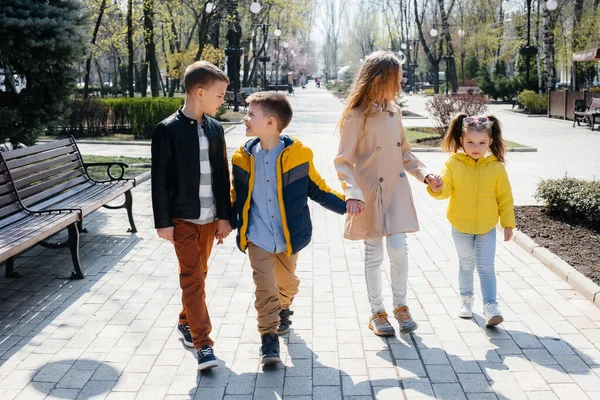 Bir grup çocuk birlikte oynuyor ve parkta el ele tutuşuyorlar. Arkadaşlar, çocuklar.