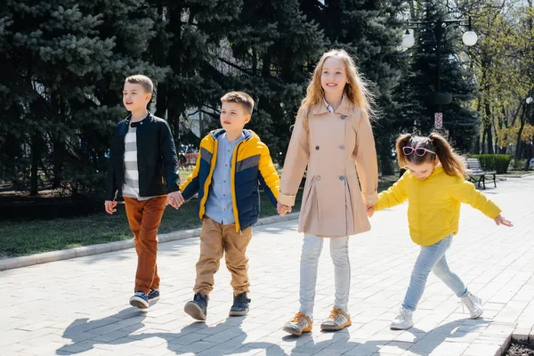 Bir grup çocuk birlikte oynuyor ve parkta el ele tutuşuyorlar. Arkadaşlar, çocuklar.