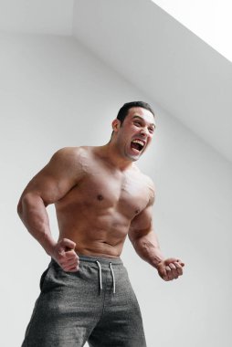 Sportif bir adam öfkeyle beyaz bir arka plana bağırıyor. Öfke. Tehdit