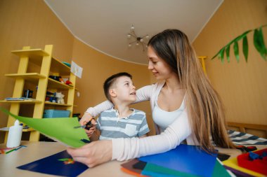 Genç bir anne evde oğluyla ev ödevi yapıyor. Ebeveynler ve eğitim