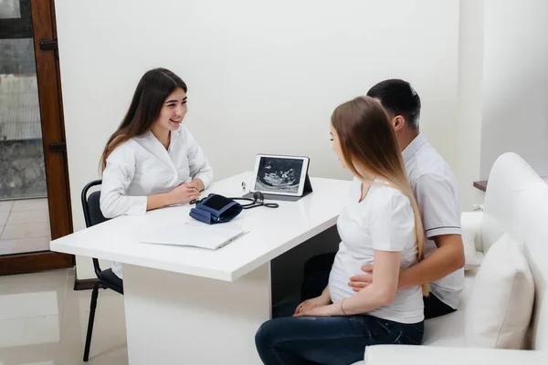 赤ん坊が超音波の後の婦人科医に相談するのを待っている若いカップル 妊娠中や健康管理 — ストック写真