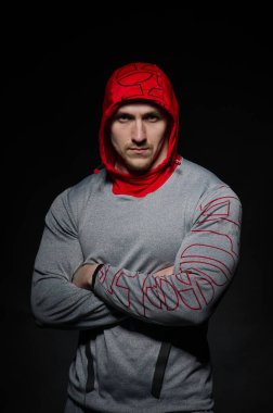 Stüdyoda kapüşonlu karanlık bir arka plana karşı duran sportif bir adam. Spor, güzellik