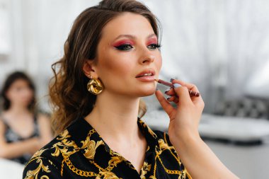 Güzel, modern bir güzellik salonunda, profesyonel bir makyöz genç bir kız için makyaj yapar. Güzellik ve moda.